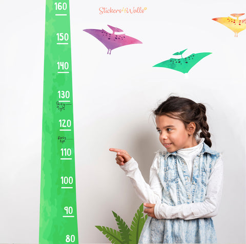 little gril pointing at a dino height chart wall sticker